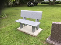 White concrete memorial bench in cemetery