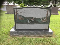 Black granite monument with etched bare trees
